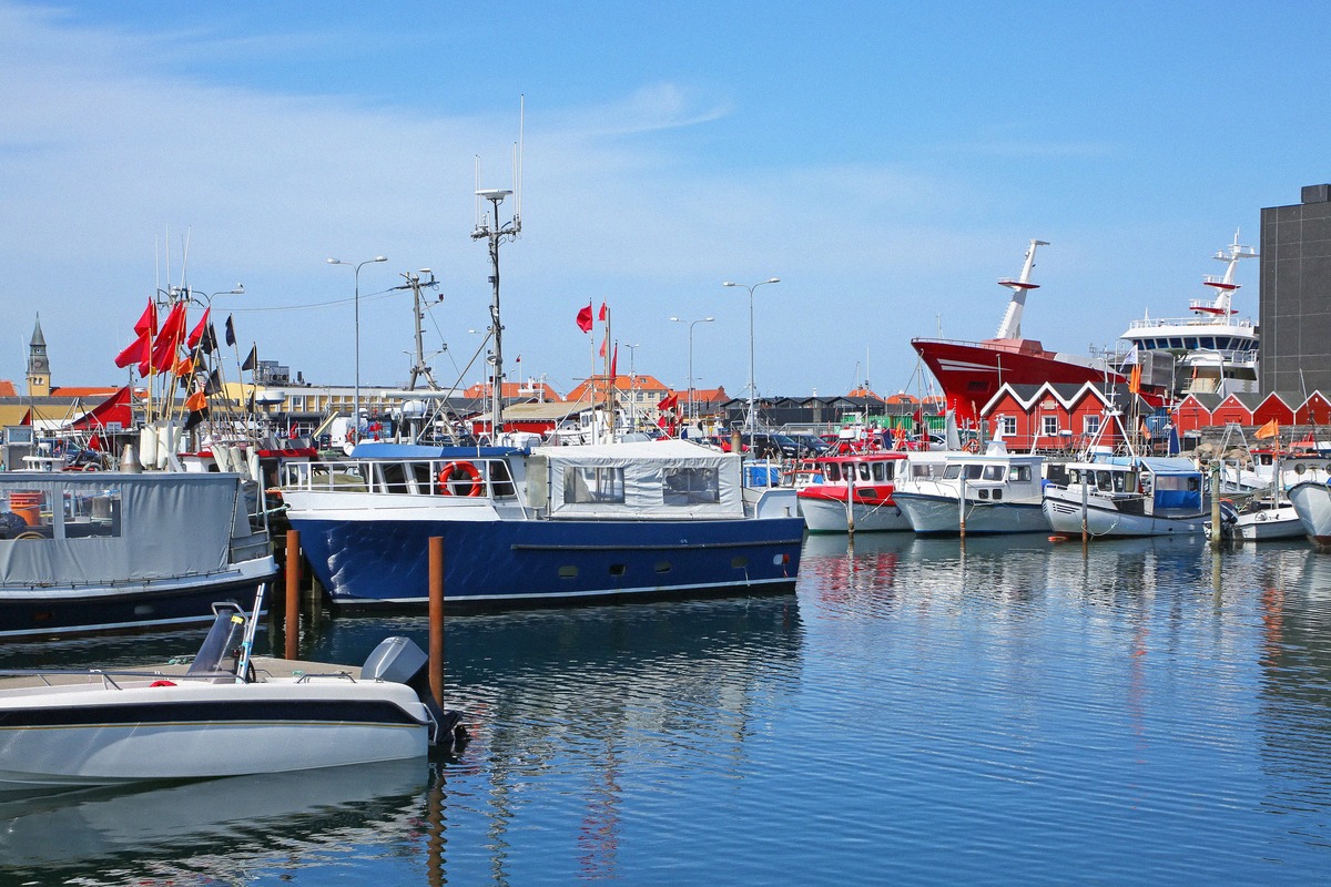 Fischkutter und Boote im Hafen von Skagen vor roten Fischhallen